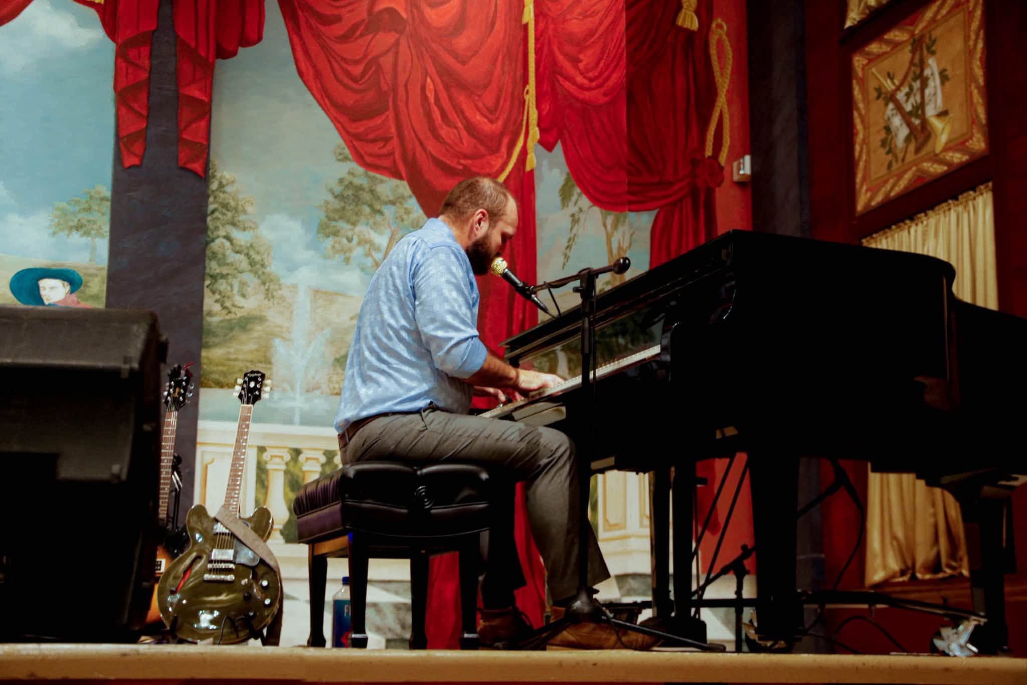 Nate Kelley seated at a grand piano on the Enid Symphony Hall stage